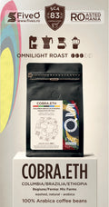 A coffee bag product display on a pedestal with branding and roast information. The main product shown is a black coffee pouch labeled COBRA. Columbia Brazilia coffee blend made from single origins.
