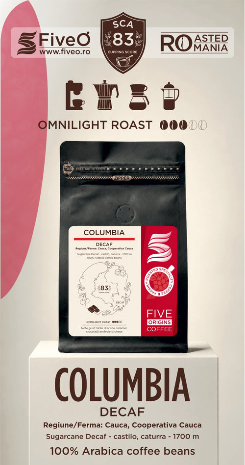 A coffee bag product display on a pedestal with branding and roast information. The central product is a black coffee bag labeled Columbia Decaf, with FiveO branding and a cream background featuring pink graphic elements and icons for coffee brewing and roasting.