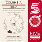 eticheta produsului Pungă de cafea Columbia Decaf Five Origins Coffee, cu note de caramel, ciocolată amăruie și cireșe, fotografiată premium pe fundal cald cu munți subtili.